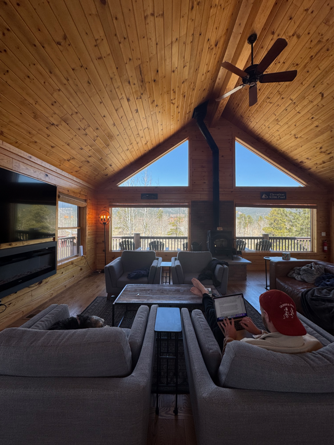 Vaulted great room with a wood ceiling, A-frame windows, and sofas gathered around a coffee table
