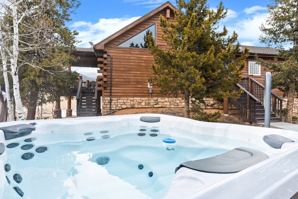 Private hot tub at Rosalie Ridge Cabin, with the cabin and pines behind it