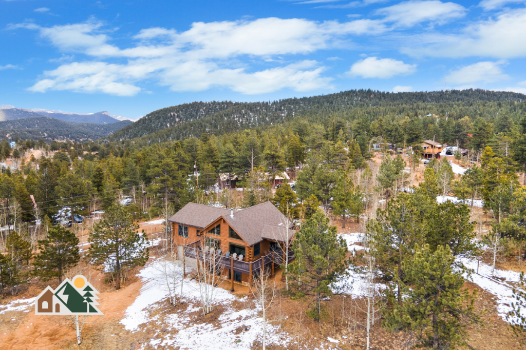 Aerial view of Rosalie Ridge Cabin among the pines, with mountains in the distance