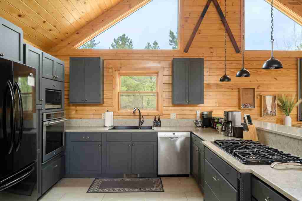 Kitchen with black appliances, a gas range, and dark cabinets under a vaulted ceiling