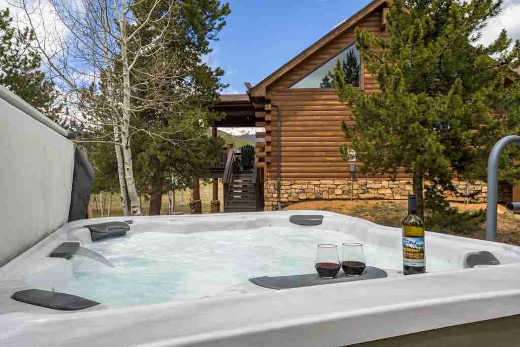 Open hot tub with the cabin and tall pines behind it
