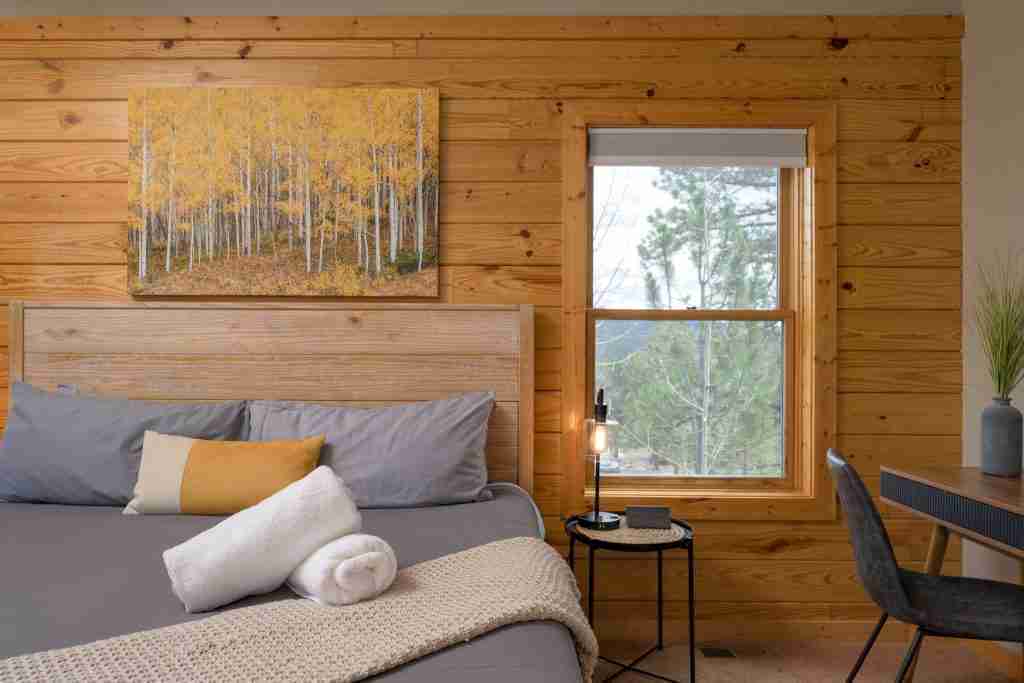 King bed with fresh towels and an aspen painting in the primary suite