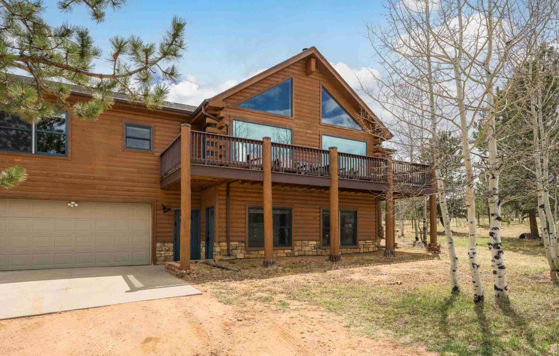 Rosalie Ridge Cabin with its wraparound deck and garage under a blue sky