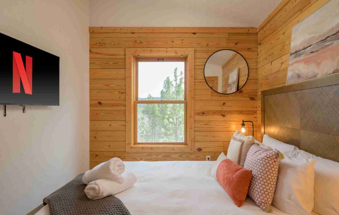 Queen bedroom with a smart TV and a window to the pines